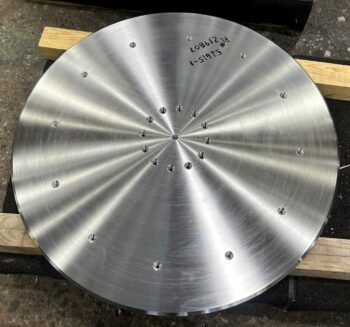 Circular machined stainless steel plate with a finished surface and multiple drilled holes.