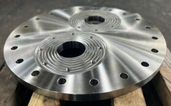 Machined circular stainless steel component with large cutouts, threaded holes, and precision-finished surfaces.