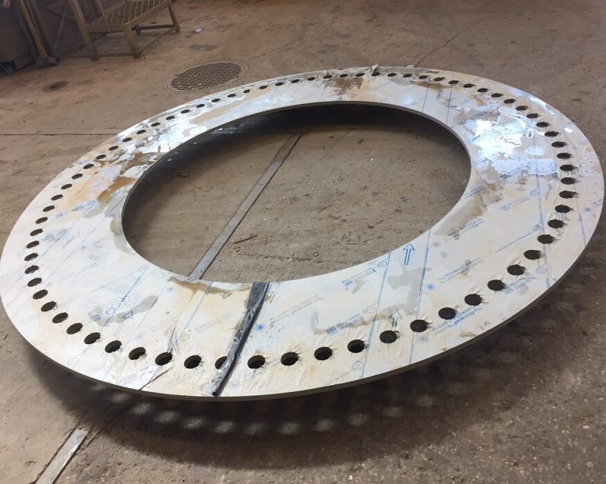 Large circular stainless steel component with precision-cut holes around the outer edge, made from 3/4” thick 316L stainless steel, produced by Sandmeyer Steel for a manufacturer in the beverage and bottling industry.