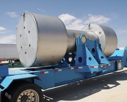 A large piece of stainless steel nuclear waste treatment equipment secured on a transport trailer.